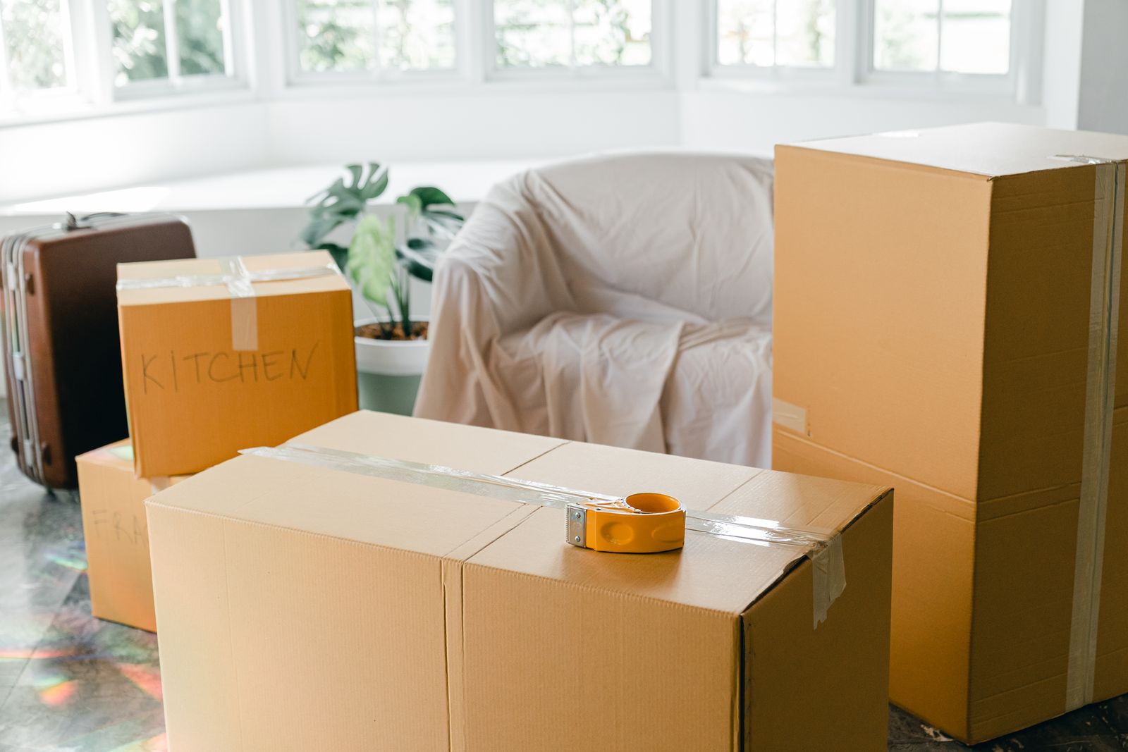 Packed cardboard boxes and a covered armchair in a room being emptied.