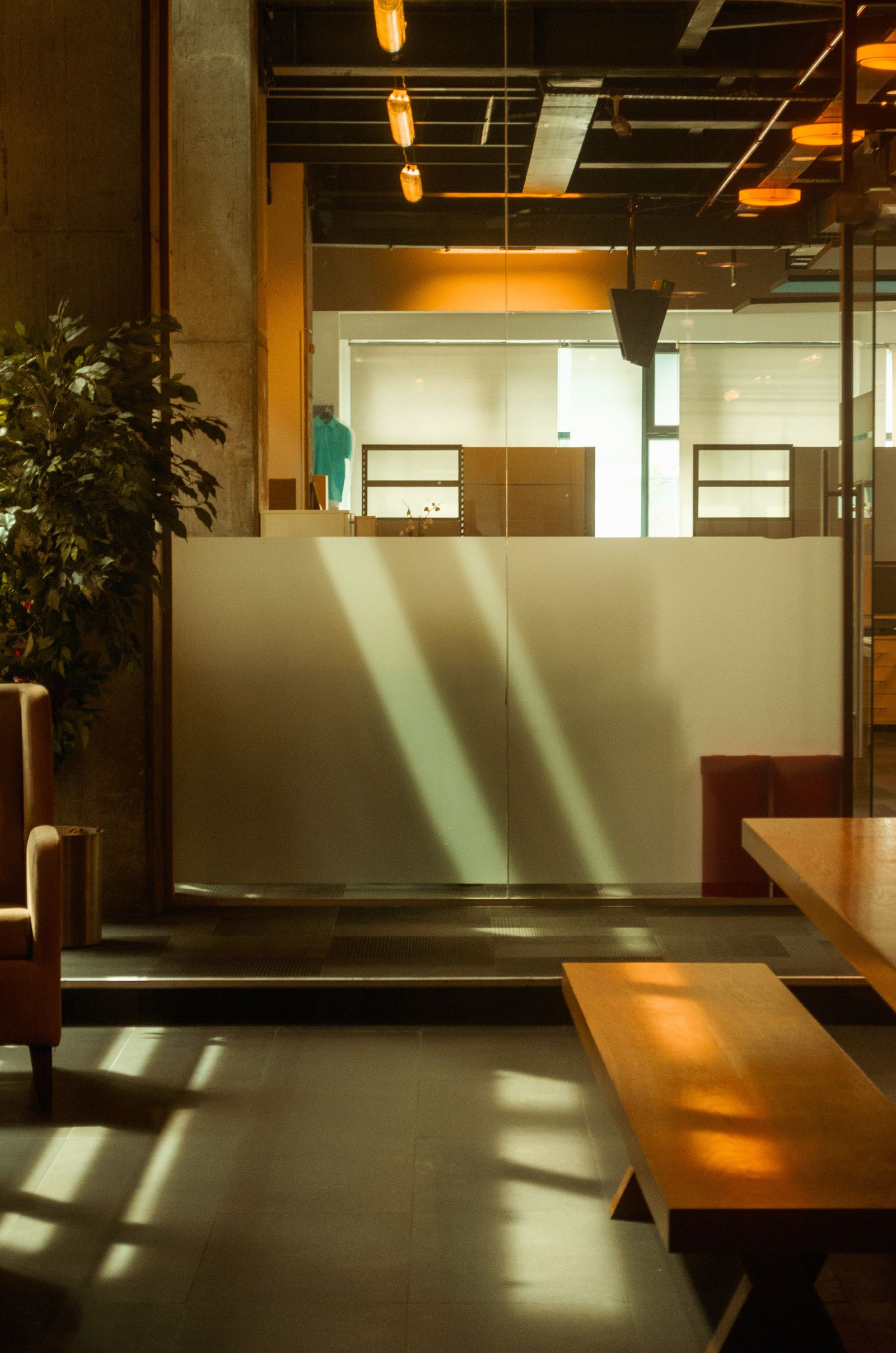 An empty waiting area in a public building, with a bench and a frosted glass partition.