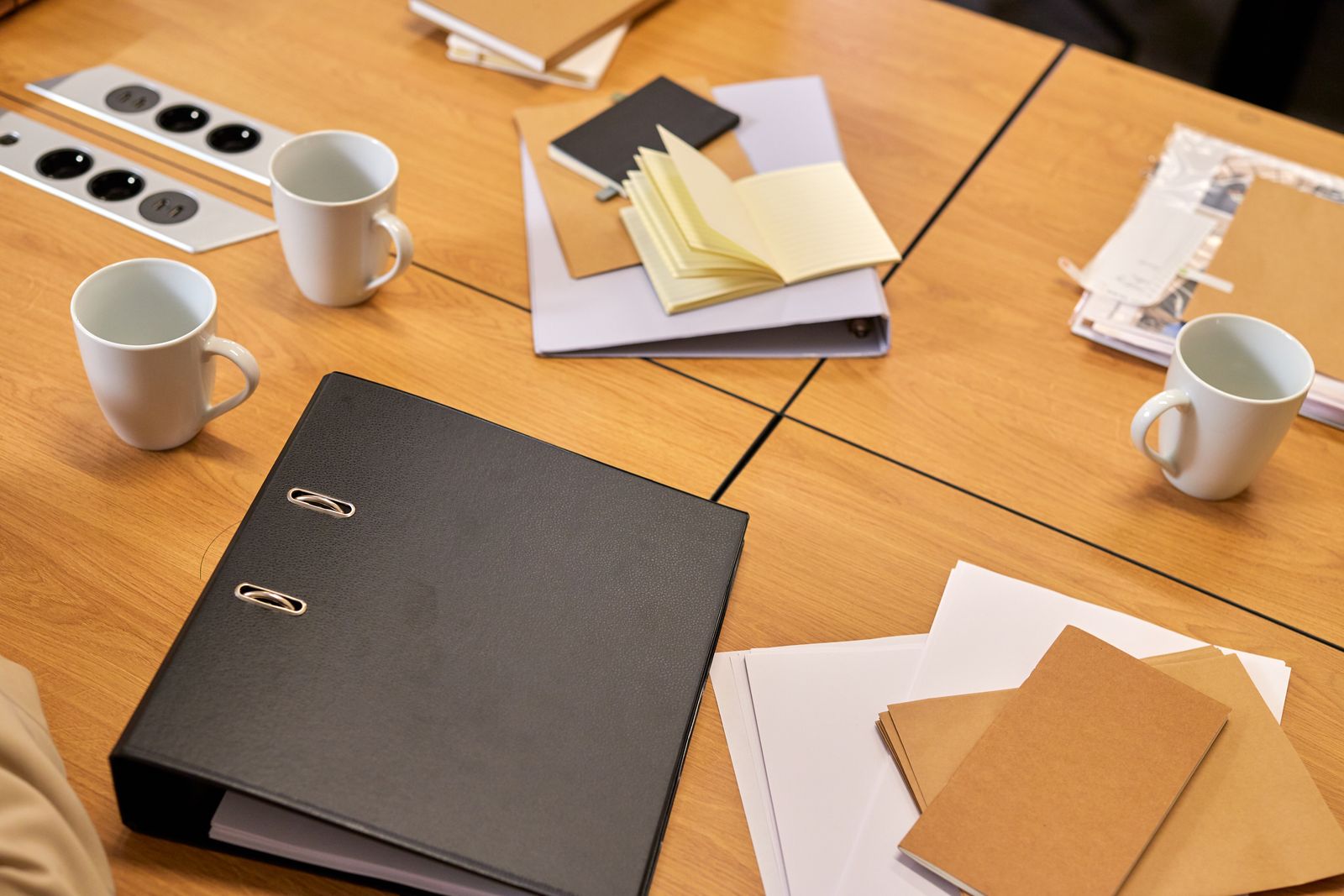 Paperwork in piles on a table with a lever-arch folder and a notebook.
