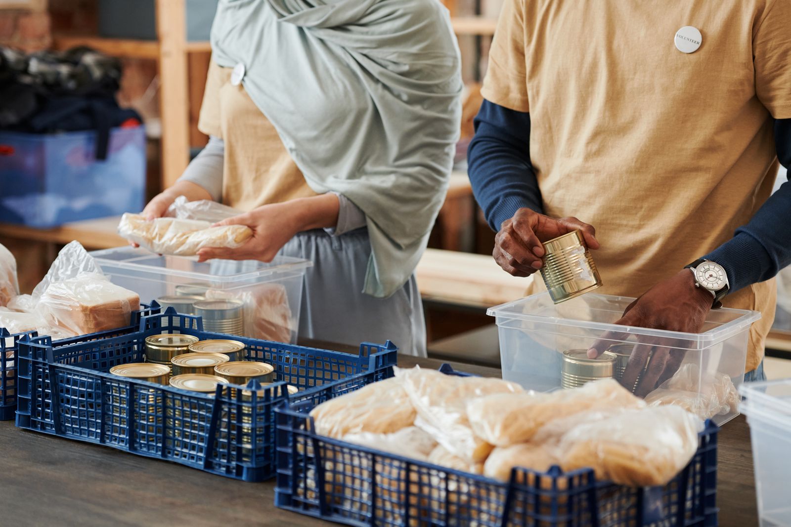 Volunteers packing bread and tinned food into crates at a community pantry.